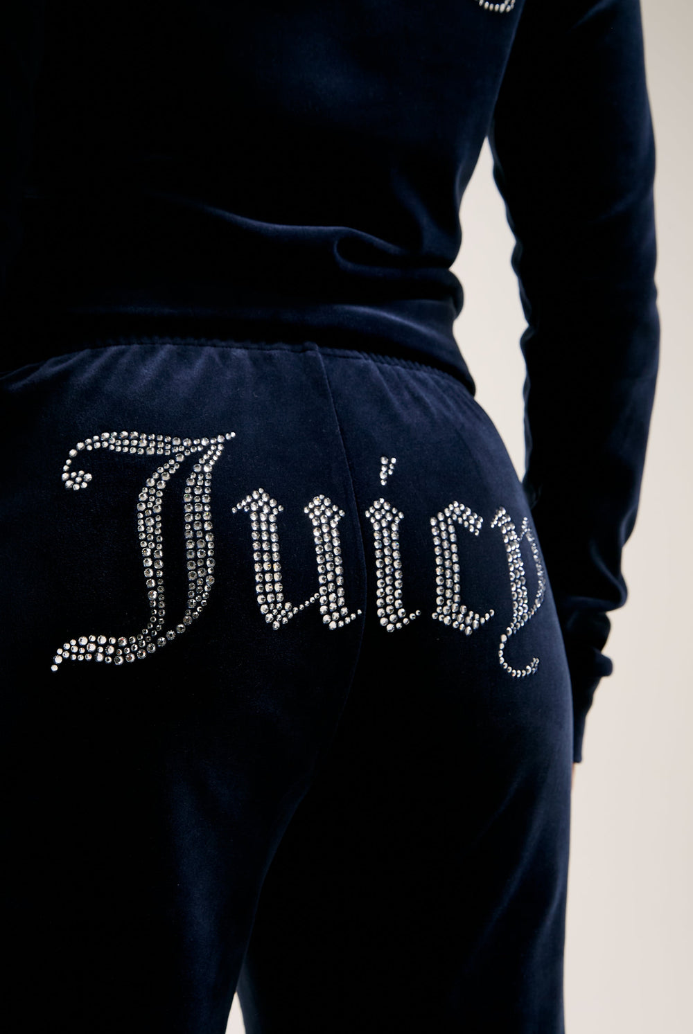 Displays a model wearing the Night Sky 'juicy' branded velour diamanté tracksuit bottom featuring the Juicy logo