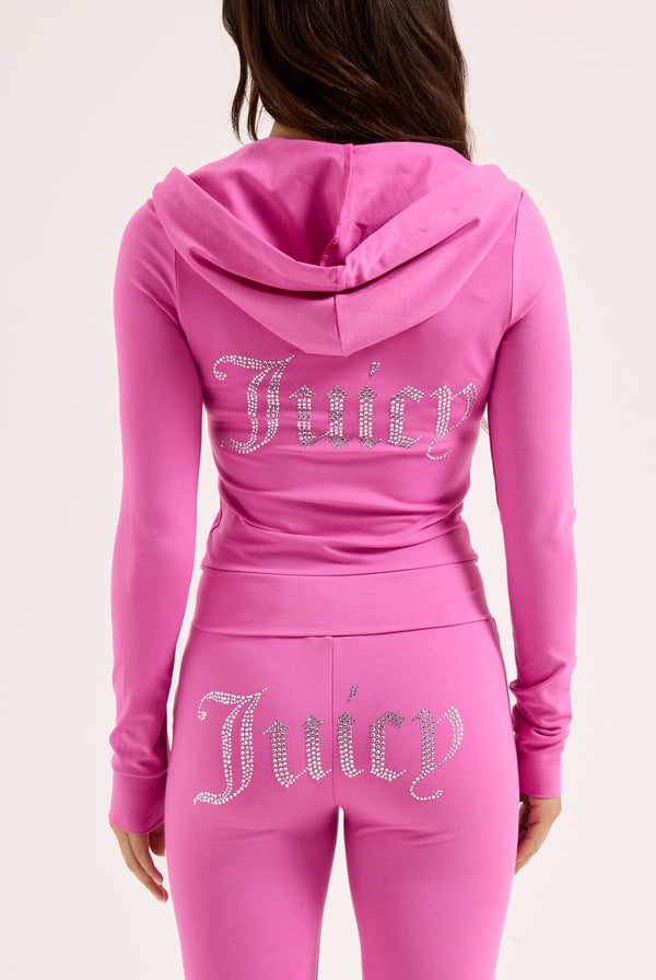 Displays a model wearing the Super Pink 'Juicy' branded Diamanté luxury jersey zip-through hoodie featuring the juicy branding 