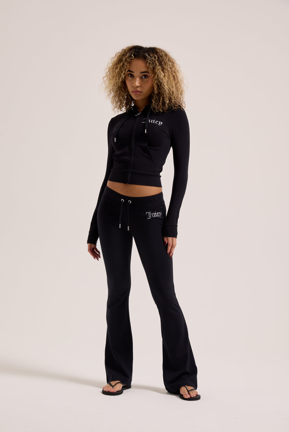Displays a model wearing the Black Diamanté 'Juicy' branded luxury jersey low rise pants 