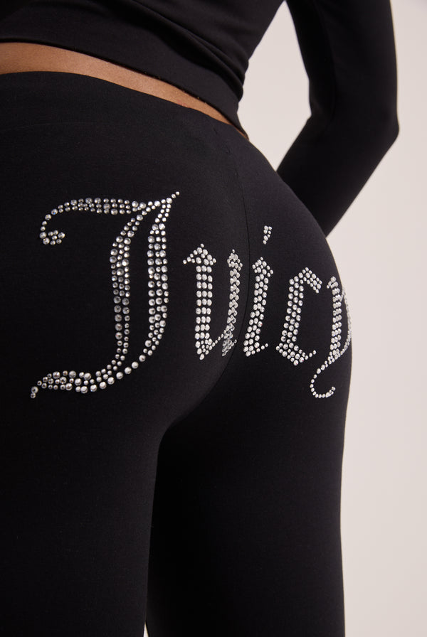 Displays a model wearing the Black Diamanté 'Juicy' branded luxury jersey low rise pants featuring the juicy branding