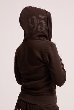 Displays a model wearing the Java longline 'Juicy' branded fleece zip through hoodie 