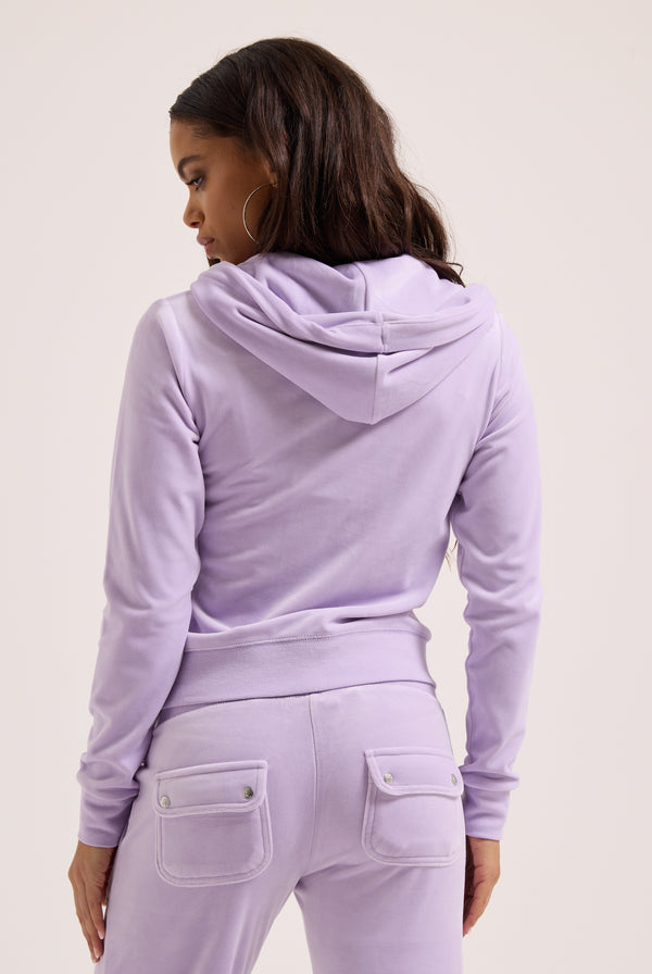 Displays a model wearing the pastel lilac 'juicy' branded low rise flare classic velour track pant 