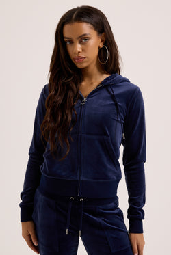 Woman wearing a navy blue tracksuit on a light background