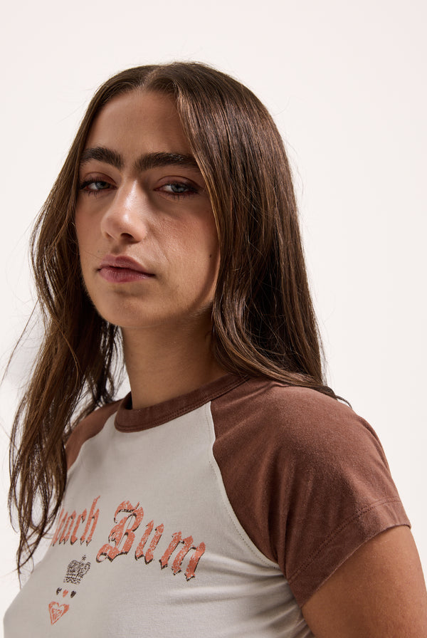 Displays a model wearing the Coconut Milk Roxy & Juicy Couture raglan graphic tee 