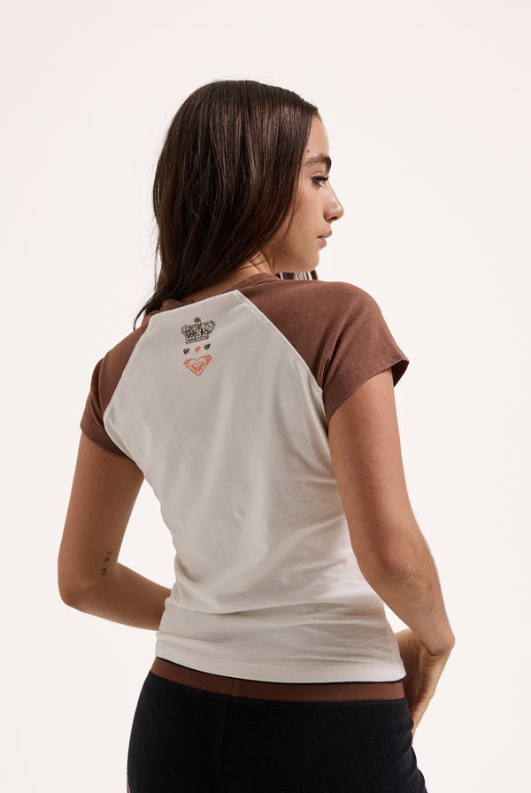 Displays a model wearing the Coconut Milk Roxy & Juicy Couture raglan graphic tee 