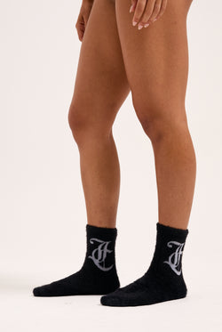 Displays a model wearing the Black seasonal 'Juicy' branded fluffy sock included in the 2 pack 