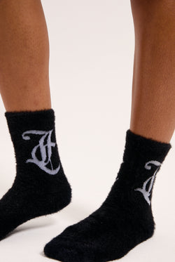 Displays a model wearing the seasonal 'Juicy' branded fluffy sock included in the 2 pack 