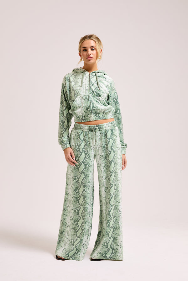 Display a model wearing the green snake print 'Juicy' branded diamanté low rise track bottom 