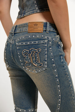Displays a model wearing the Mid Wash 'Juicy' branded Sand Stud Moto Bootcut Jeans