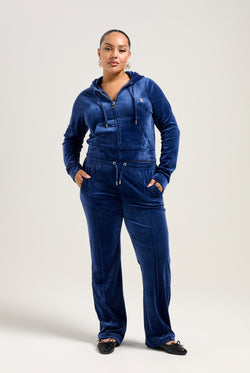 Displays a model wearing the Blue Depths 'Juicy' branded velour diamanté tracksuit bottom 
