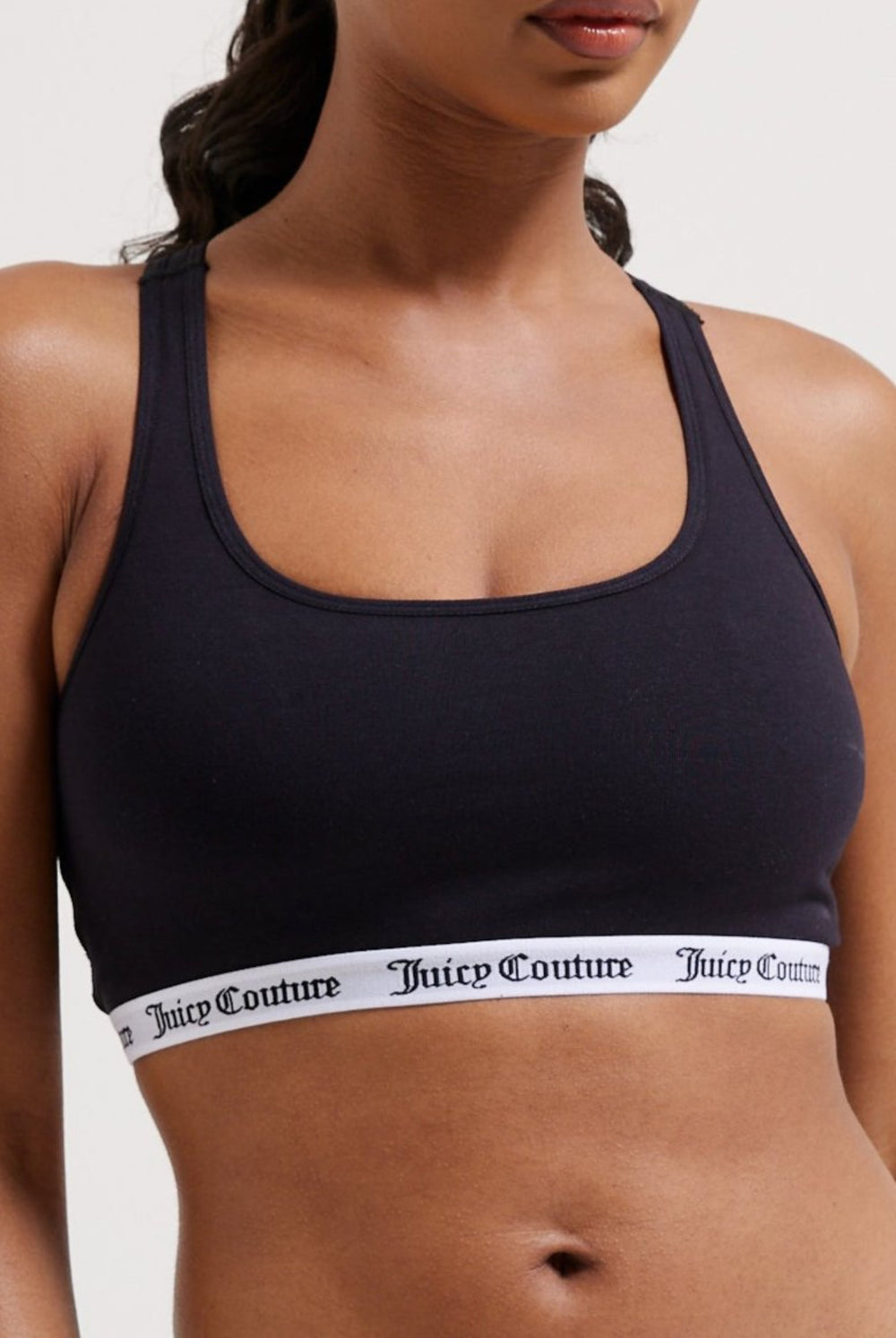 Displays a model wearing the Black 'juicy' branded cotton bralette 