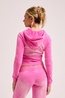Displays a model wearing the super pink washed 'juicy' branded cotton velour fitted hoodie 