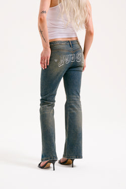 Displays a model wearing the Vintage Wash 'Juicy' branded western diamanté flared jeans 