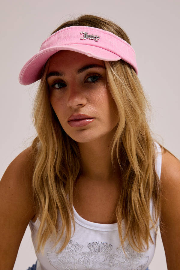 Displays a model wearing the pink distressed 'juicy' branded cotton denim visor  