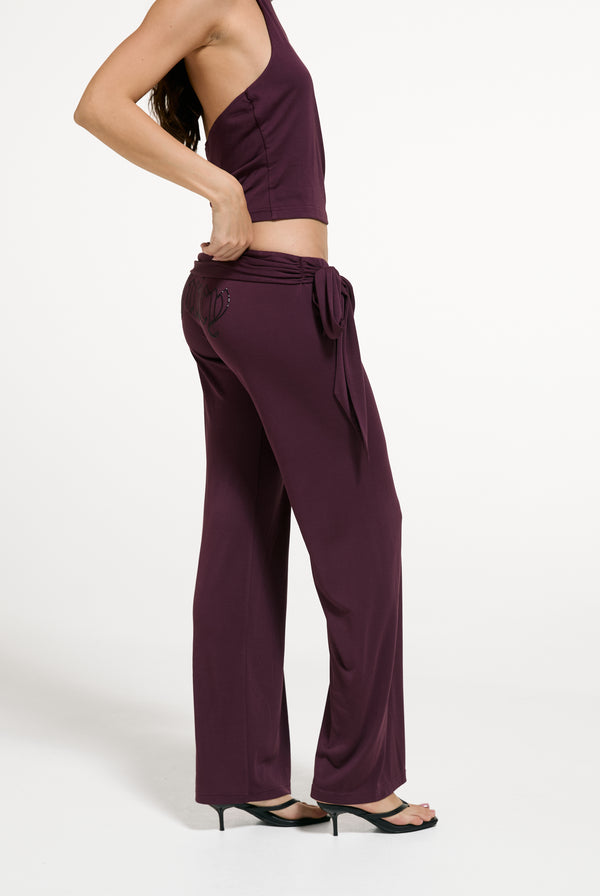 Displays a model wearing the Winetasting 'Juicy' branded Belted Flare Trousers