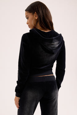 Displays a model wearing the washed black cotton 'Juicy' branded velour og straight low rise pants 