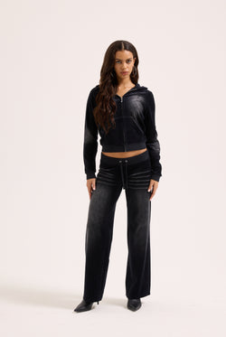 Displays a model wearing the washed black cotton 'Juicy' branded velour heritage hoodie 