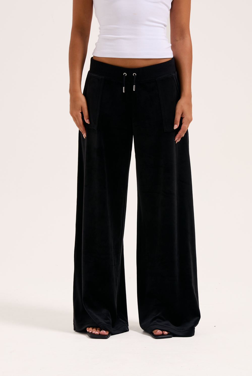 Display a model wearing the Black 'Juicy' branded wide leg classic velour track pant 