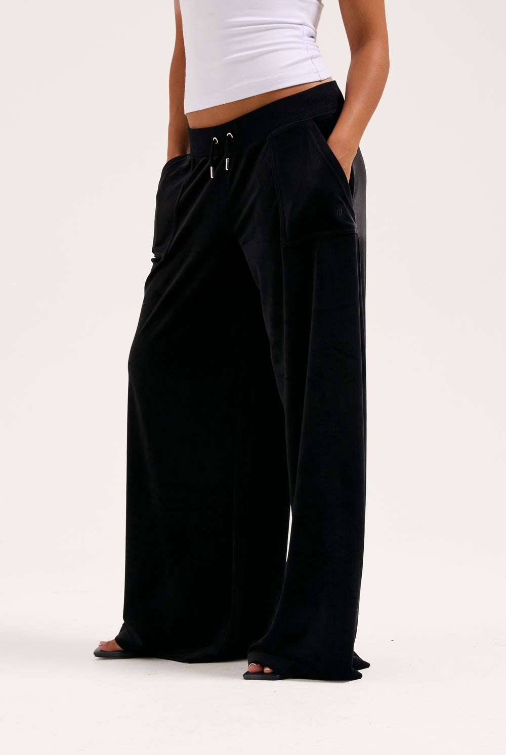 Display a model wearing the Black 'Juicy' branded wide leg classic velour track pant 