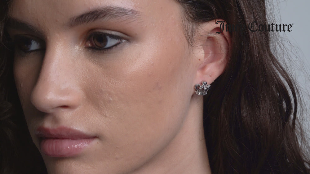 Displays a model wearing the 'Juicy' Silver Tone Crystal Icon Crown Stud Earrings