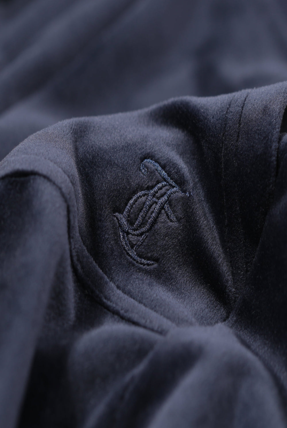 Close up of the Juicy Couture logo on a Navy Blue velour hoodie